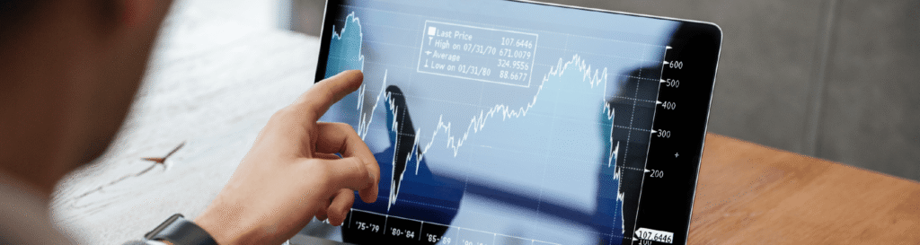 Tela do computador com gráficos e uma mão com dedo indicador apontando um dos resultado